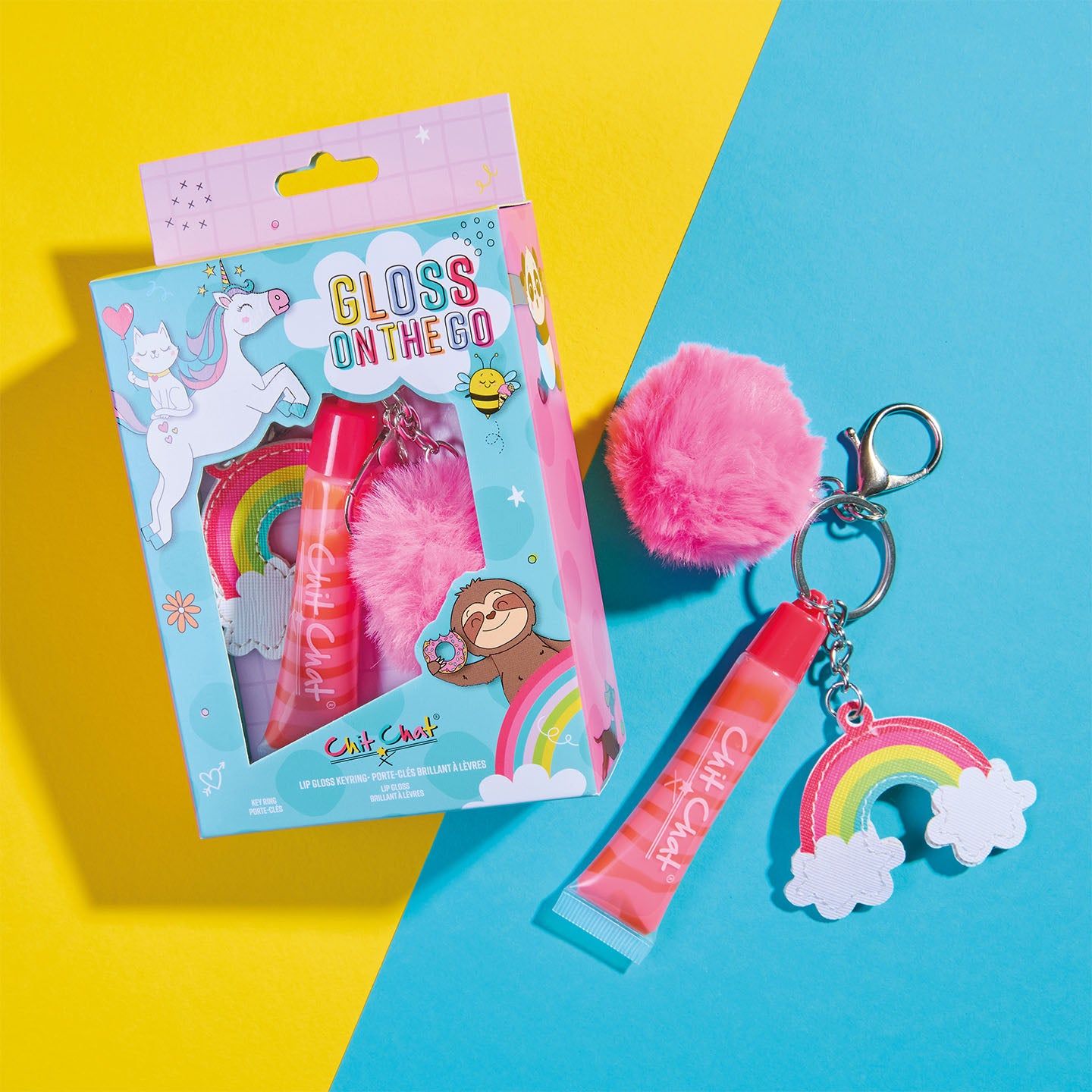 Pink lip gloss keychain with rainbow charm and pink pom-pom, with illustrated box on a colourful background